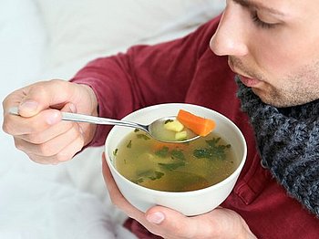 Ein Mann isst Hühnersuppe - diese ist bei Erkältungen immer noch ein bewährtes Hausmittel