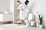 Frau im Badezimmer Junge Frau steht im Badezimmer vor der Toilette