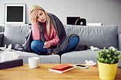 Frau erkältet Hier sieht man eine erkältete Frau auf dem Sofa.