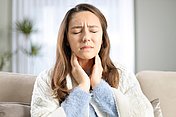 Diese Frau hat erste Anzeichen einer Erkältung in Form von Halsschmerzen